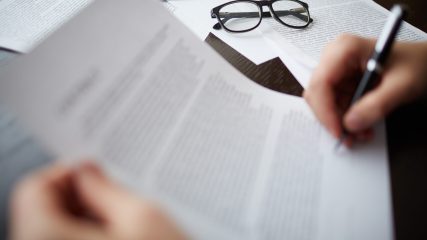 Image of business objects with businessman hand signing contract near by